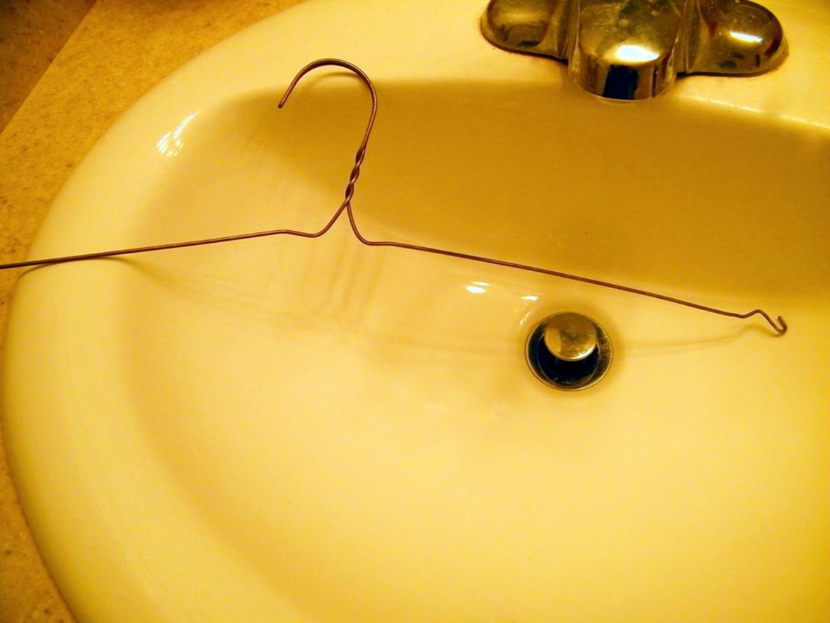 wire hanger being used to unclog a bathroom sink drain